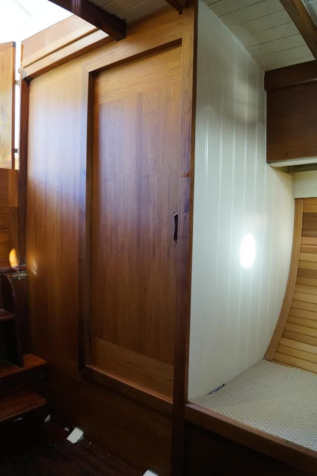 Hardwood hanging locker beside a white panelled berth