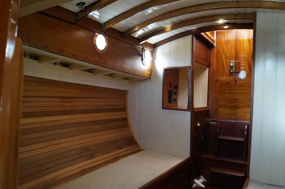 Saloon with slatted berth back, portholes and companionway steps